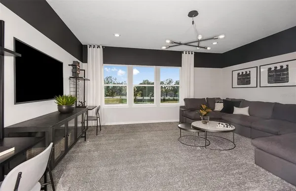 a living room with furniture a flat screen tv and a large window
