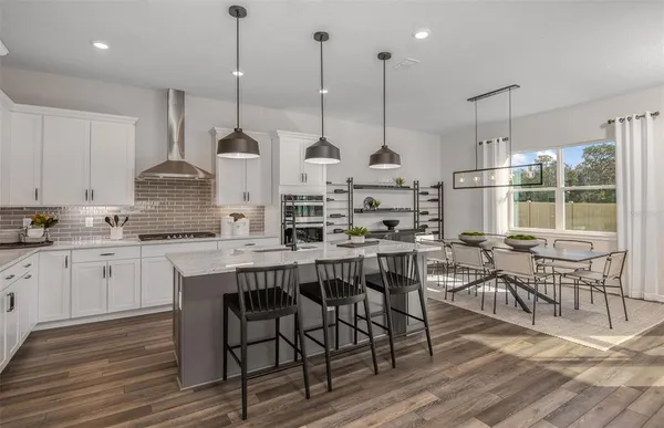 a kitchen with stainless steel appliances granite countertop a stove a kitchen island a dining table and chairs with wooden floor