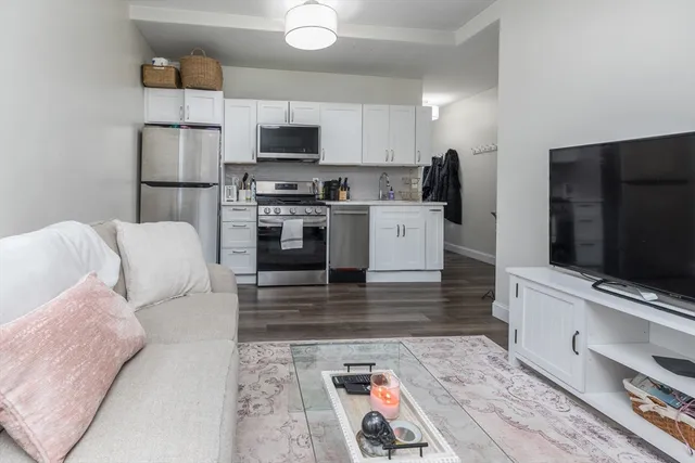 a living room with stainless steel appliances furniture and a flat screen tv