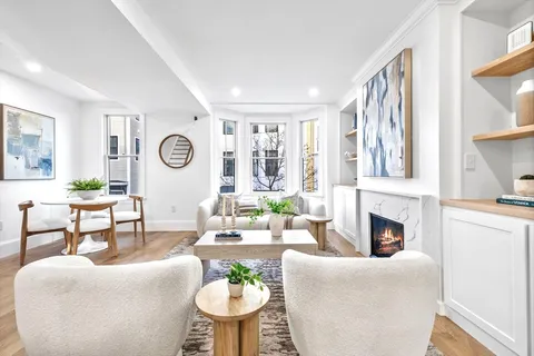 a living room with furniture a fireplace and a large window