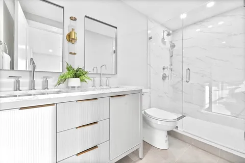 a bathroom with a sink toilet double vanity and shower