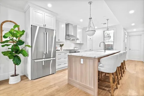 a kitchen with stainless steel appliances granite countertop a refrigerator a sink dishwasher and white cabinets with wooden floor