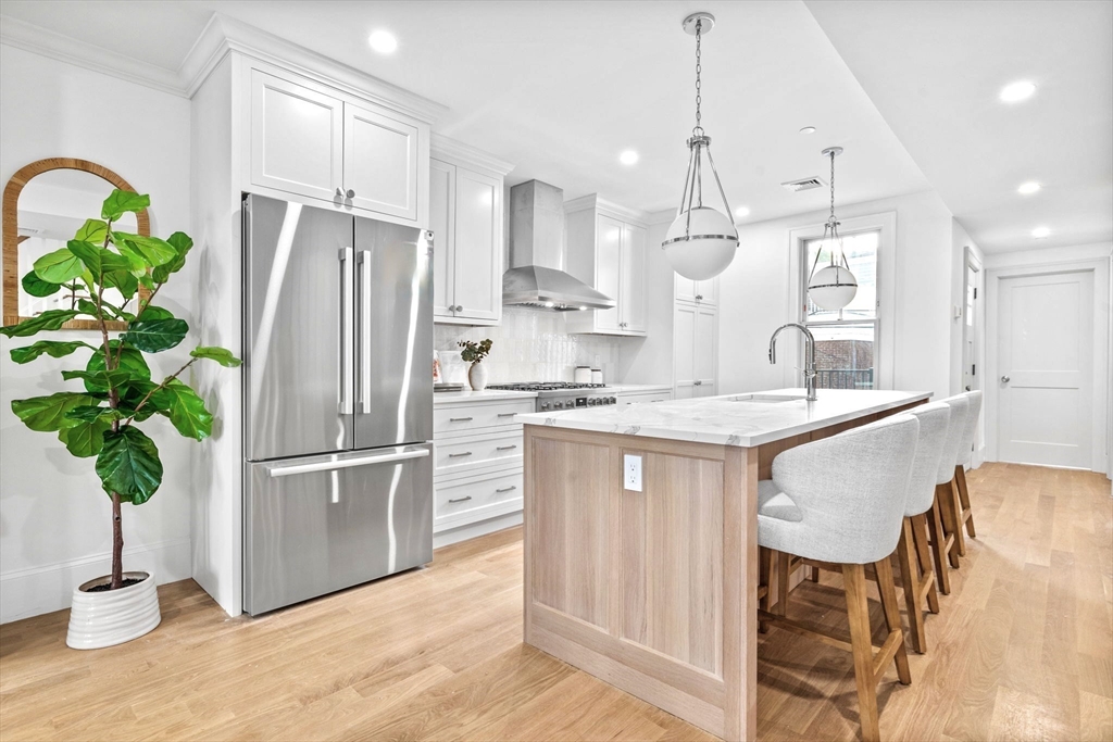 12 Prospect Street, Unit 2 Boston, MA 02129 - Photo 2 of 27 a kitchen with stainless steel appliances granite countertop a refrigerator a sink dishwasher and white cabinets with wooden floor