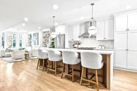 a kitchen with kitchen island granite countertop a dining table chairs and white cabinets