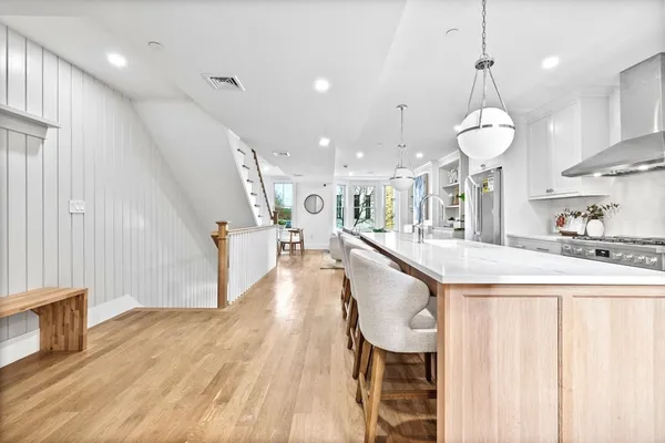 a large kitchen with kitchen island a island a stove a wooden floor and a chandelier