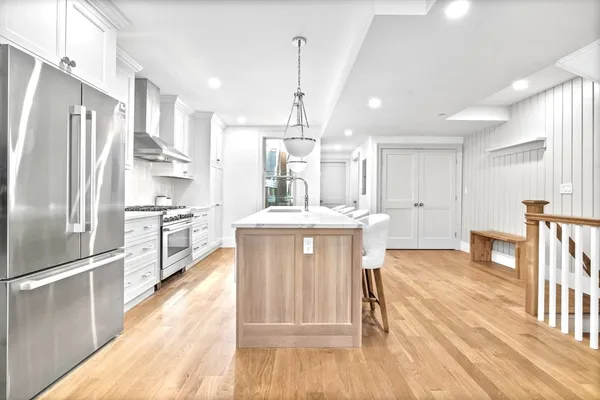 a kitchen with kitchen island a counter top space a sink stainless steel appliances and cabinets