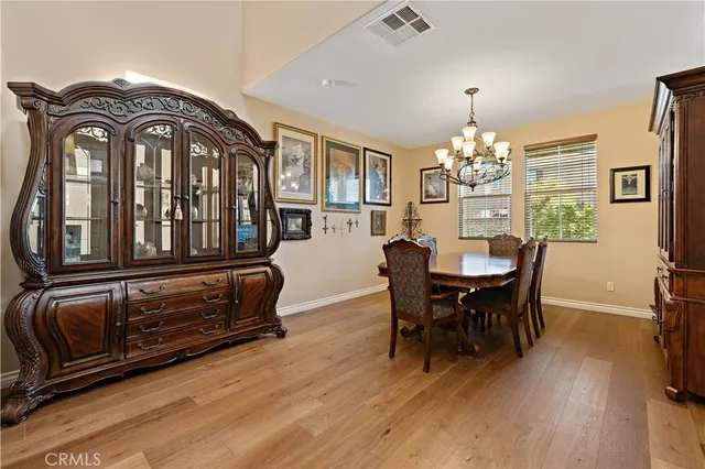 a dining room with wooden floor a chandelier a wooden table and chairs