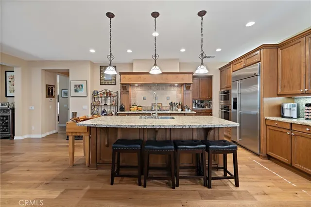 a kitchen with stainless steel appliances granite countertop a stove refrigerator and a wooden cabinets