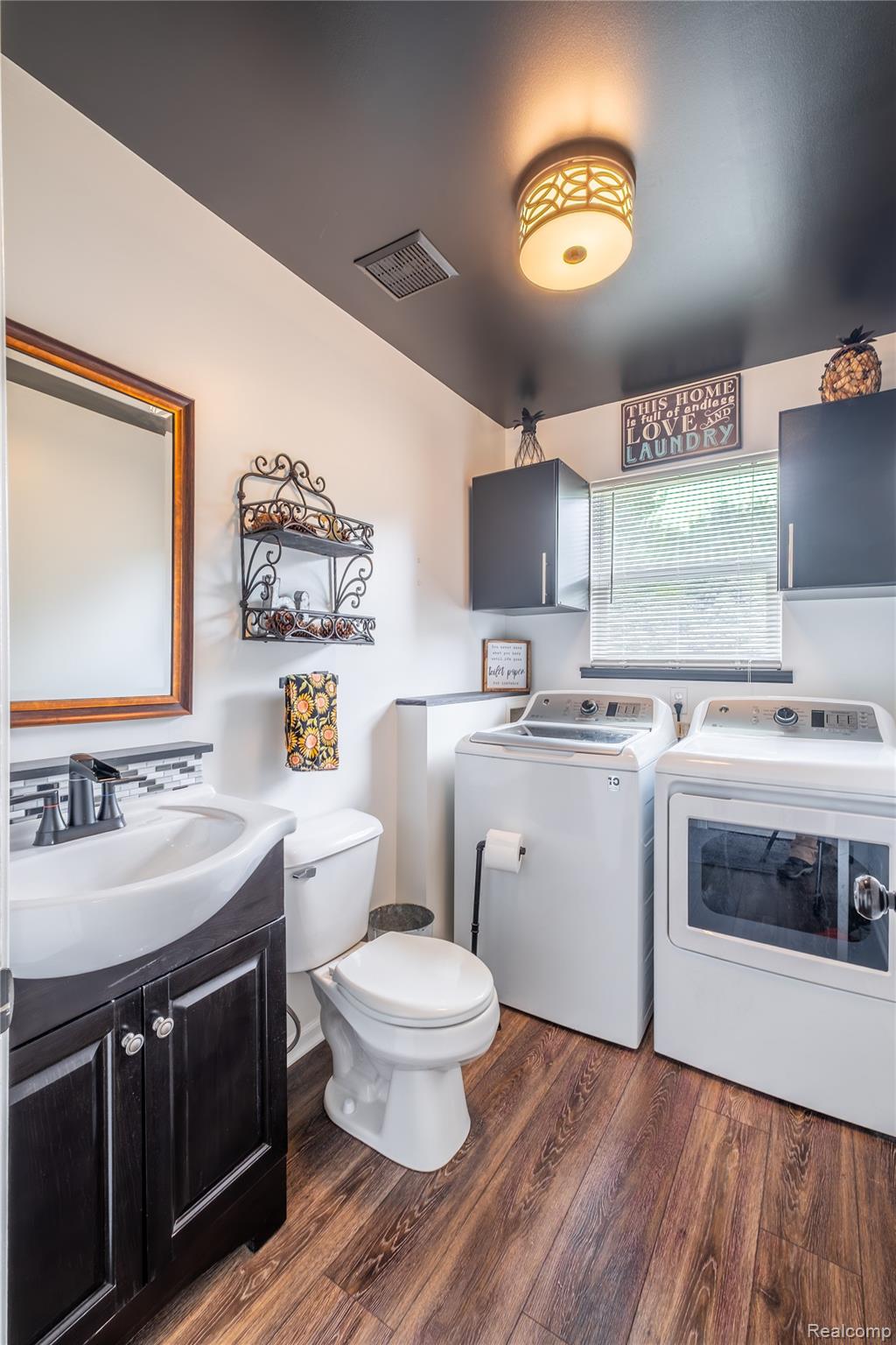 13063 Seymour Road Gaines, MI 48436 - Photo 14 of 29 Wood-finish flooring, dark wood vanity with white vessel sink, black faucet, and mosaic tile backsplash