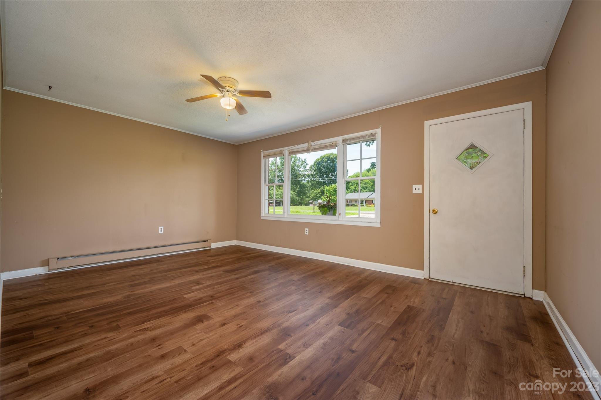 1034 Old Stonecutter Road Rutherfordton, NC 28139 - Photo 4 of 27 an empty room with wooden floor chandelier fan and windows