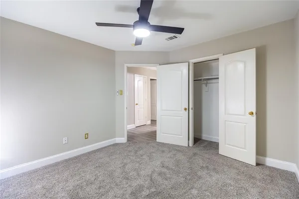 a view of an empty room and chandelier fan