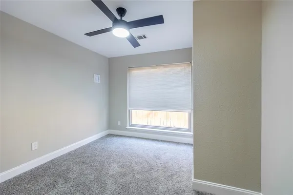 an empty room with a window and a fan