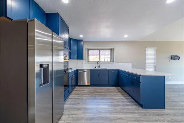 a large kitchen with stainless steel appliances granite countertop a refrigerator and a sink