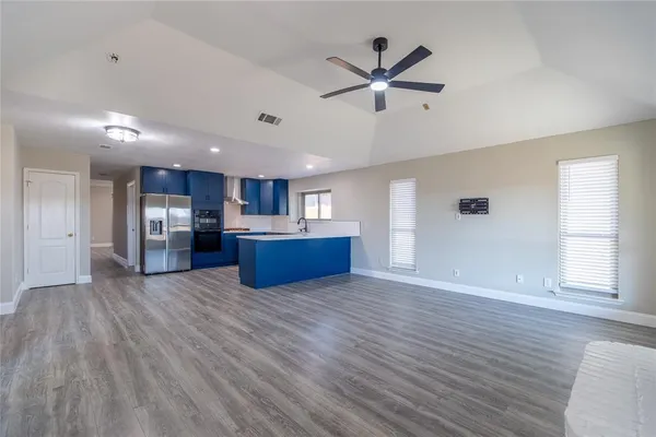 a view of kitchen and empty room with wooden floor