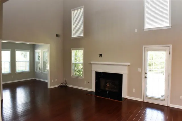 an empty room with wooden floor fireplace and windows
