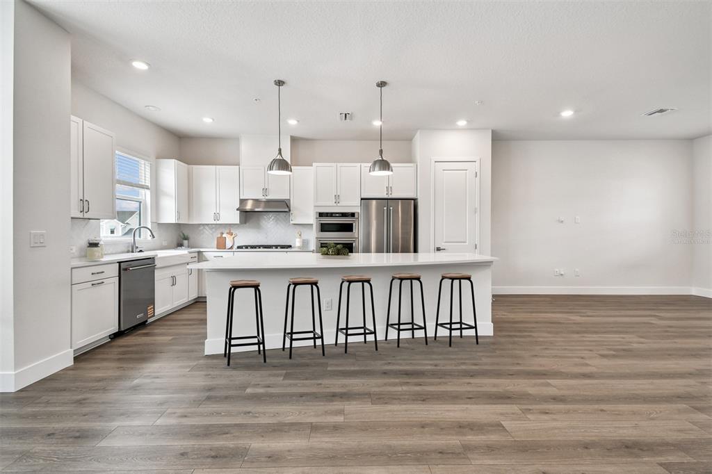 7204 Sutton Lane Sarasota, FL 34240 - Photo 9 of 47 a kitchen with kitchen island granite countertop a sink cabinets and wooden floor