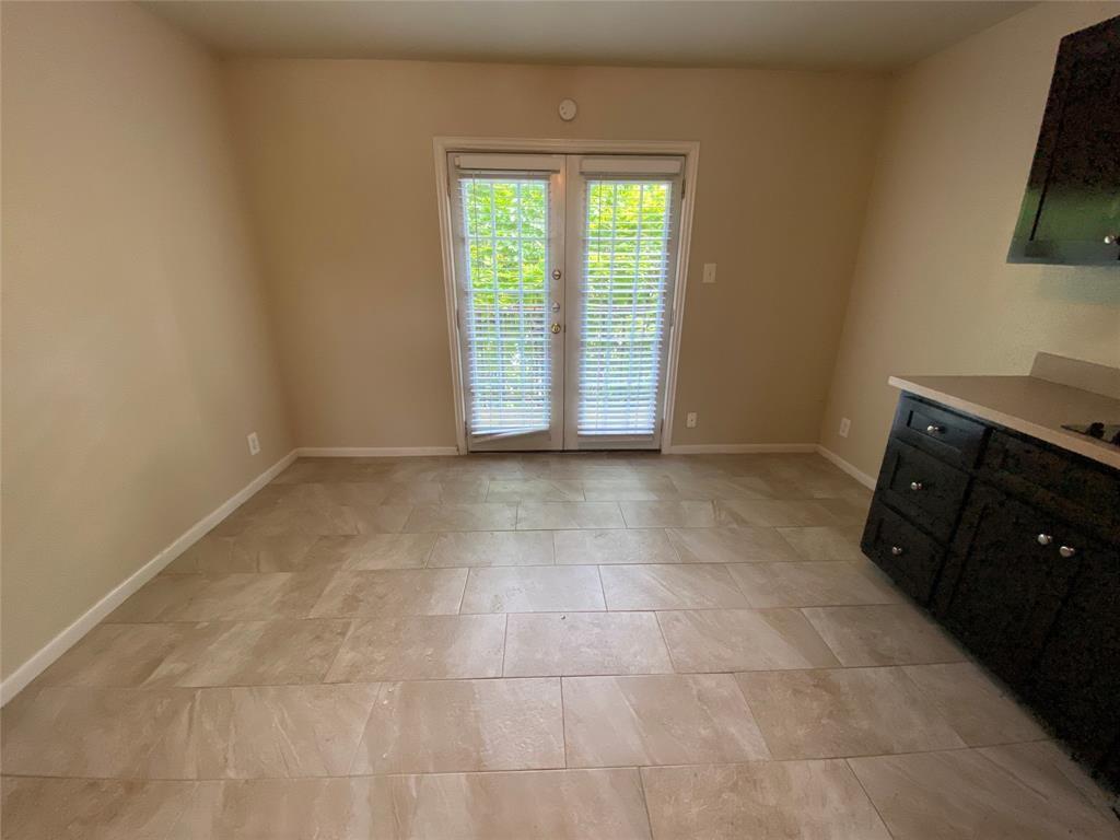 2402 Rio Grande Street, Unit 4 Austin, TX 78705 - Photo 4 of 5 French doors with white blinds, light-toned tile flooring, and a base cabinet with a light countertop