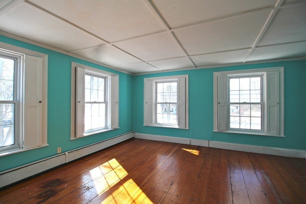 68 County Road, Unit 1 Ipswich, MA 01938 - Photo 21 of 22 an empty room with wooden floor and windows with curtains