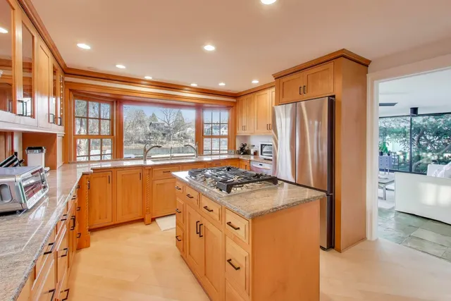 a kitchen with stainless steel appliances granite countertop a refrigerator a stove and a sink with wooden floor
