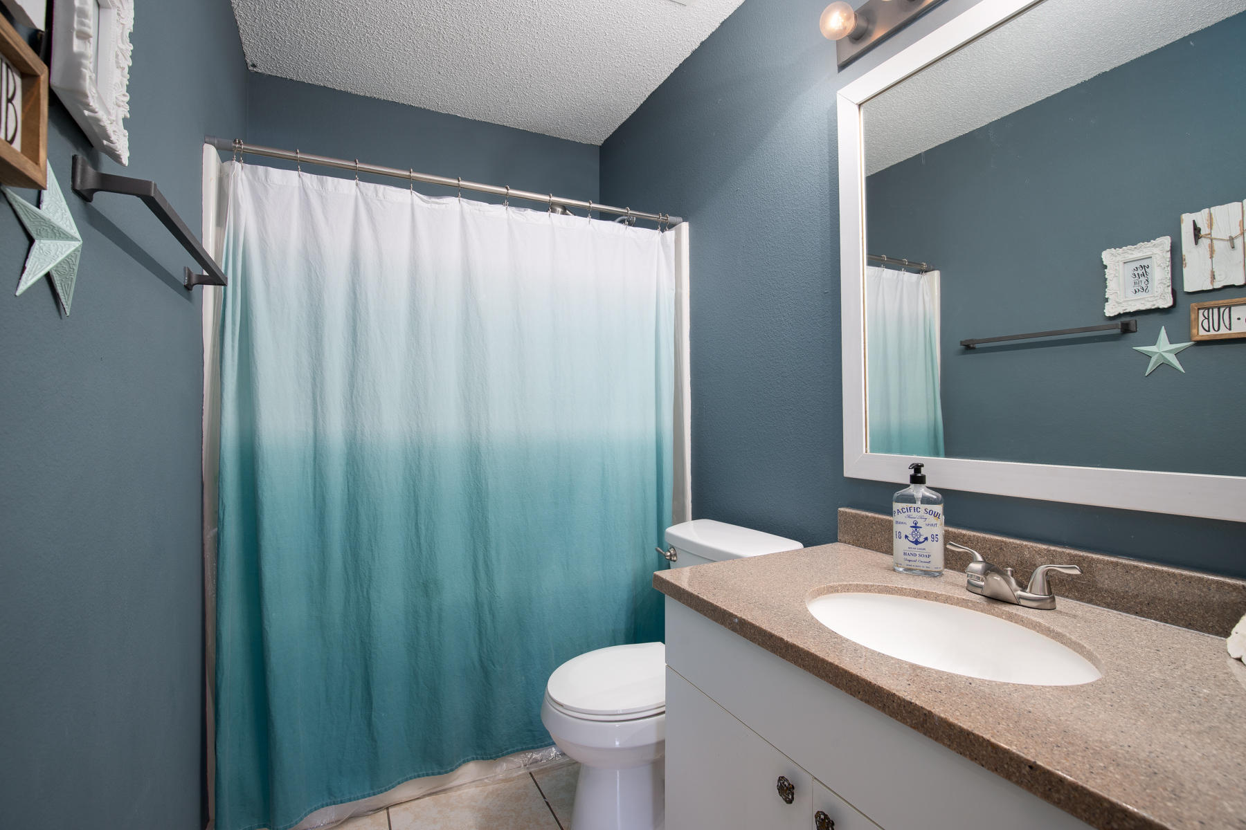 2774 Augustus Road Navarre, FL 32566 - Photo 13 of 18 a bathroom with a granite countertop toilet a sink and a mirror