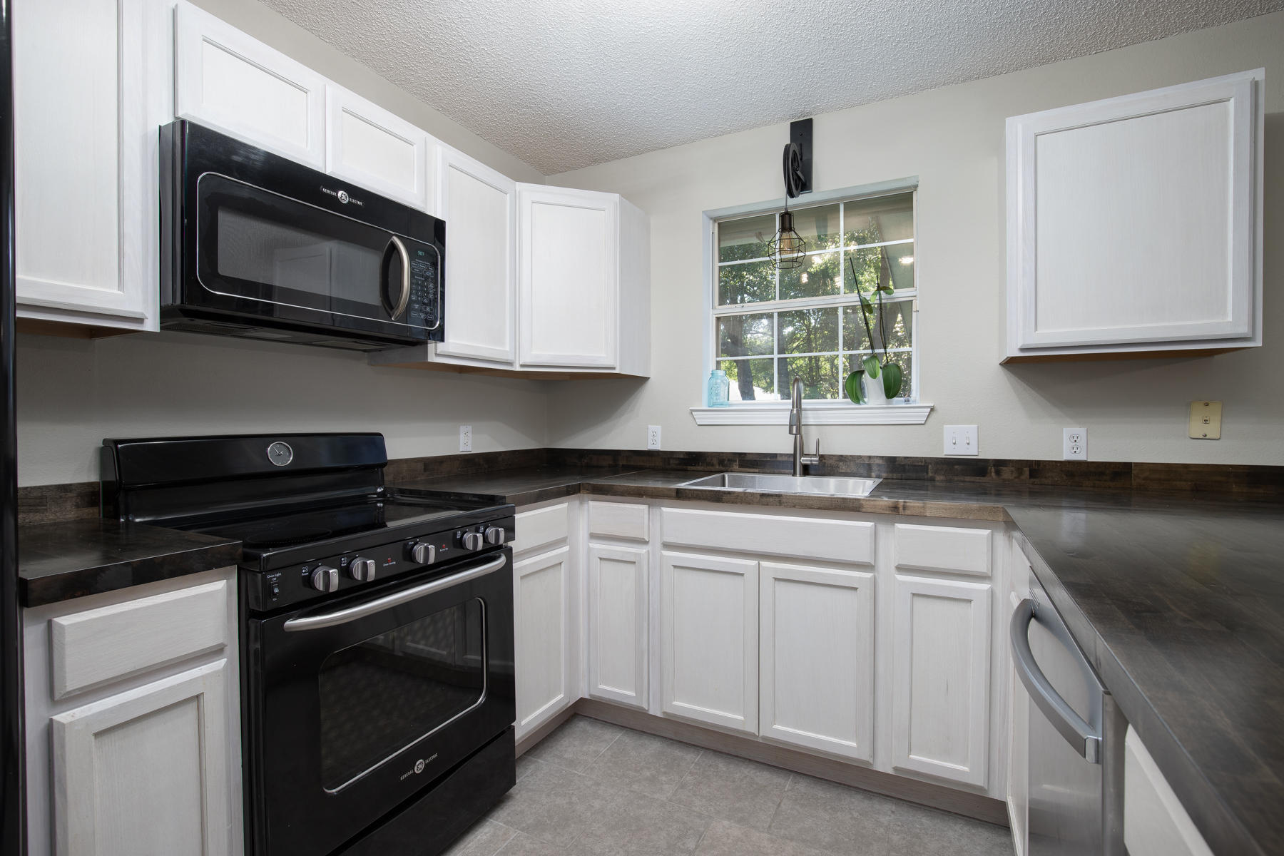 2774 Augustus Road Navarre, FL 32566 - Photo 8 of 18 a kitchen with stainless steel appliances granite countertop a sink a stove and microwave