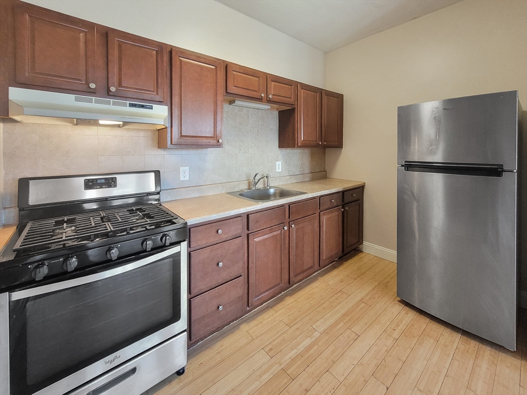 338-342 Warren Street, Unit 3 Boston, MA 02119 - Photo 2 of 7 a kitchen with stainless steel appliances granite countertop a stove a refrigerator and a sink