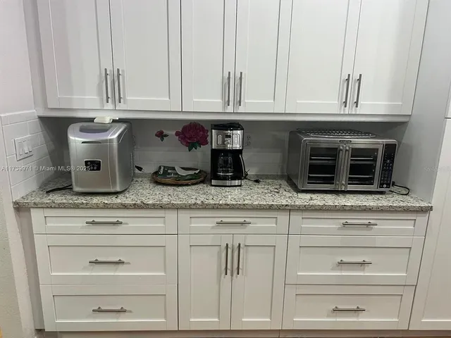 a kitchen with granite countertop white cabinets and a stove