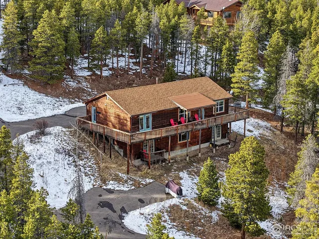 a aerial view of a house with large trees and lawn chairs