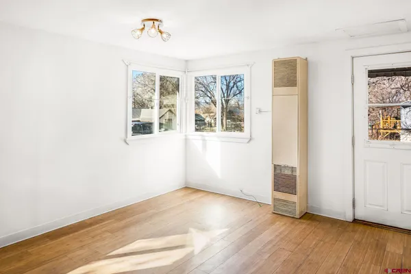 an empty room with wooden floor and windows