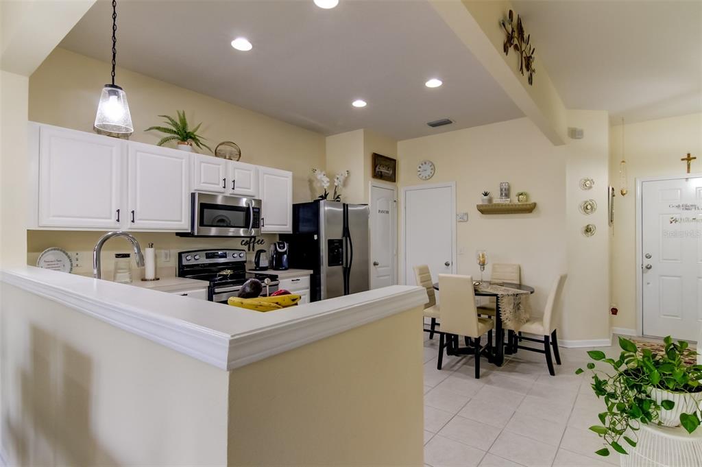 26642 Castleview Way Wesley Chapel, FL 33544 - Photo 13 of 50 a kitchen with stainless steel appliances a microwave a stove a refrigerator a sink a dining table and chairs with white cabinets