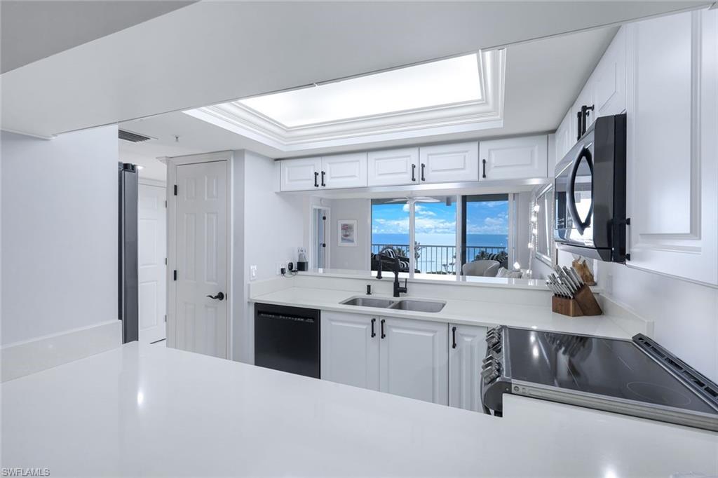 50 Seagate Drive, Unit 703 Naples, FL 34103 - Photo 15 of 34 a kitchen with sink cabinets and window