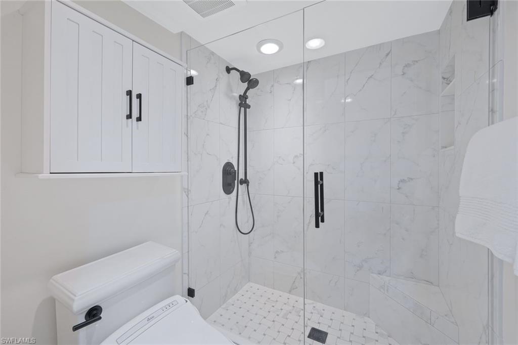 50 Seagate Drive, Unit 703 Naples, FL 34103 - Photo 24 of 34 a bathroom with a shower a toilet and sink