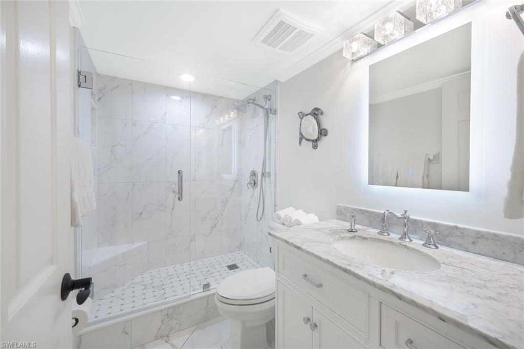 50 Seagate Drive, Unit 703 Naples, FL 34103 - Photo 26 of 34 a bathroom with a granite countertop sink a toilet and shower