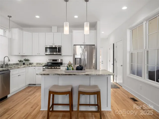 a kitchen with stainless steel appliances granite countertop a stove a sink refrigerator and a wooden cabinets with wooden floor