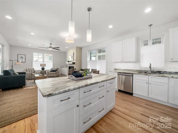 a large kitchen with kitchen island a sink dishwasher a stove a dining table and chairs with wooden floor