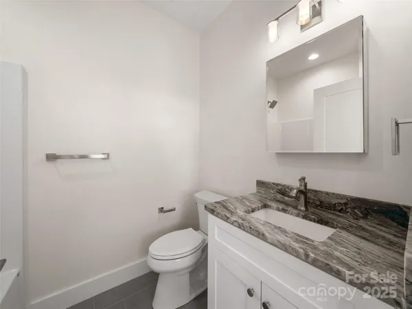a bathroom with a granite countertop sink a toilet and a mirror