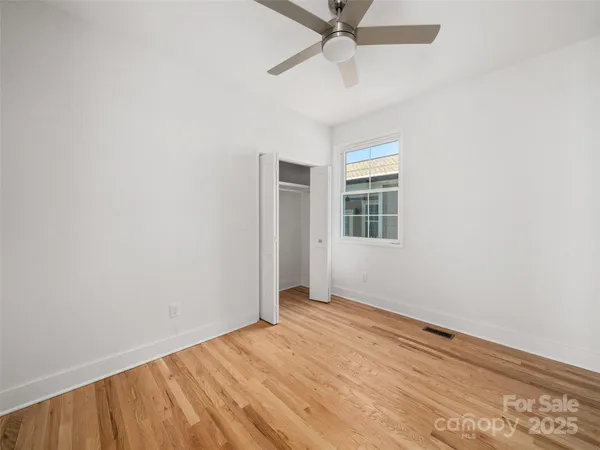 an empty room with a window and a fan