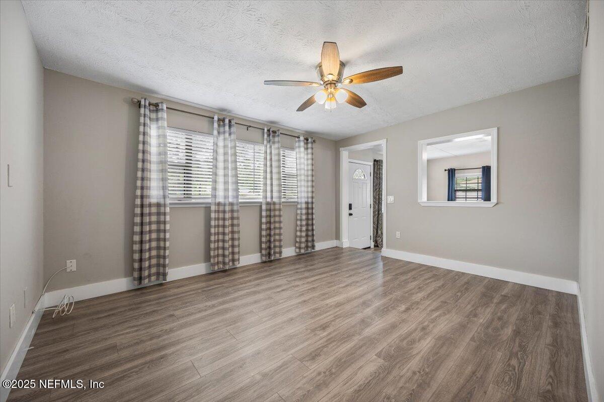 9379 Orme Road Jacksonville, FL 32220 - Photo 4 of 19 an empty room with wooden floor fan and windows