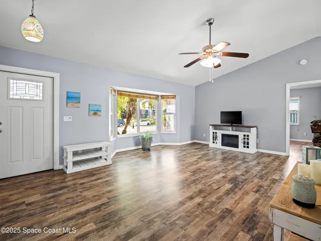 a view of a livingroom with furniture wooden floor chandelier and windows