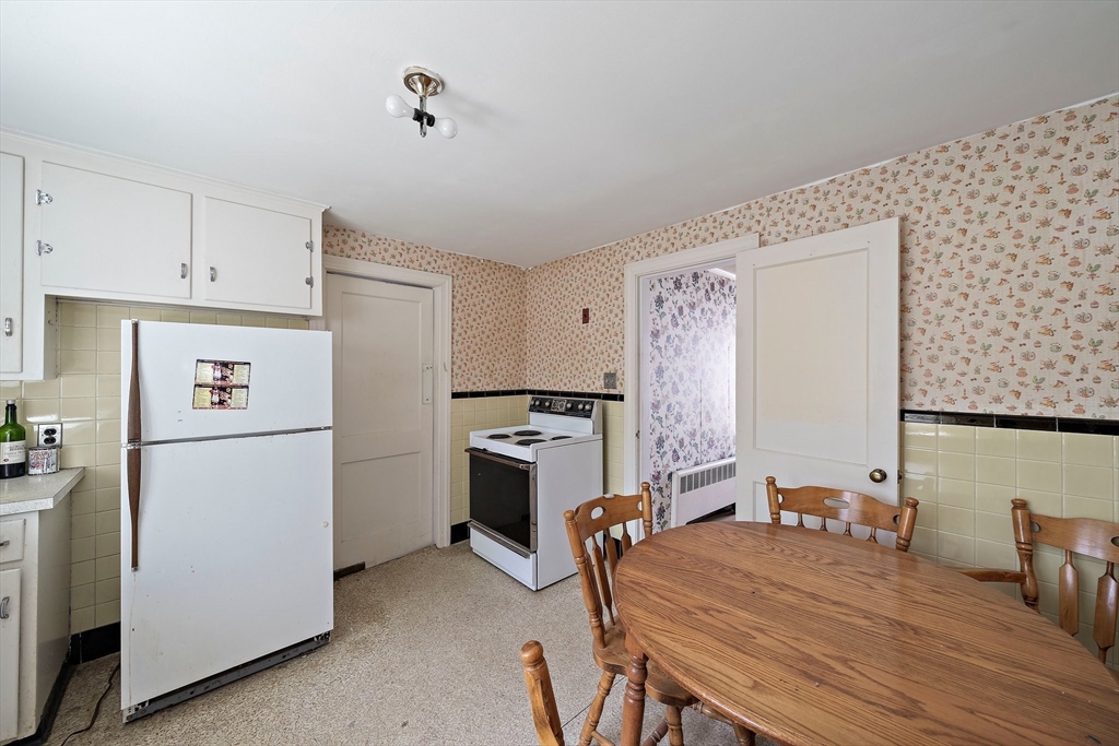 11 Latin Road Boston, MA 02132 - Photo 4 of 30 a room with a refrigerator a stove a dining table and chairs