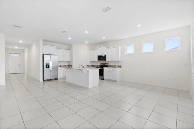 a view of kitchen with center island stainless steel appliances refrigerator sink and cabinets