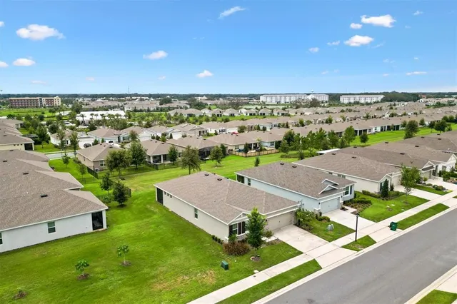 an aerial view of residential houses with outdoor space and trees