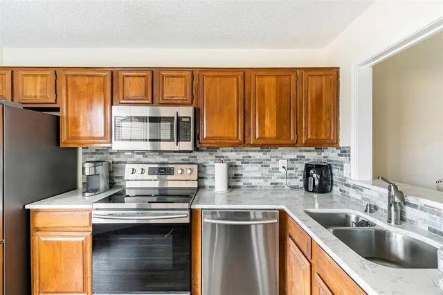 a kitchen with stainless steel appliances granite countertop a sink stove and refrigerator