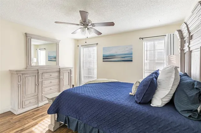 a spacious bedroom with a bed a dresser and wooden floor