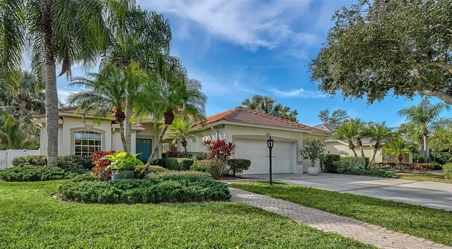 a front view of a house with a garden and palm trees