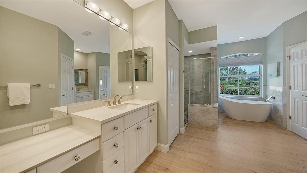 4855 Carrington Circle Sarasota, FL 34243 - Photo 28 of 58 a spacious bathroom with a double vanity sink large mirror and a bathtub