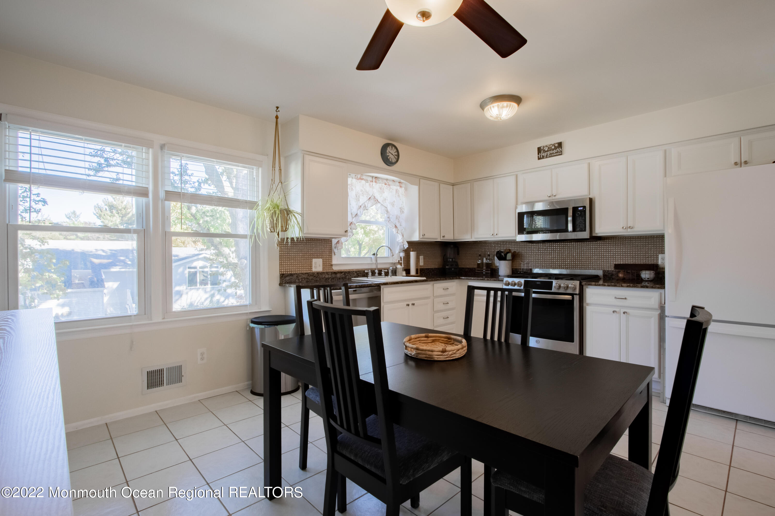 73 Ravine Drive Matawan, NJ 07747 - Photo 7 of 15 a kitchen with stainless steel appliances granite countertop a stove a refrigerator a microwave a dining table and chairs