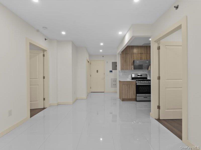 124-28 Queens Boulevard, Unit 12A Queens, NY 11415 - Photo 6 of 16 Kitchen with stainless steel gas range oven, recessed lighting, light tile patterned flooring, modern cabinets, and brown cabinetry