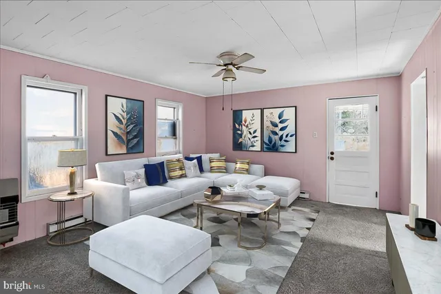 an empty room with chandelier fan and kitchen view
