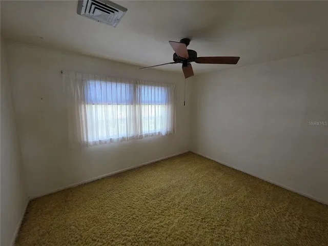 an empty room with windows and fan